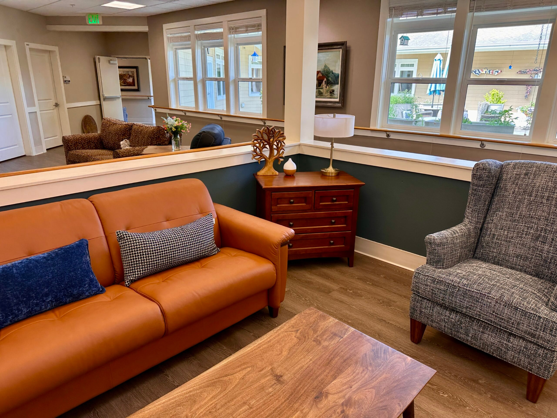 Sitting area with a tan leather sofa, patterned armchair and a handrail along a half wall